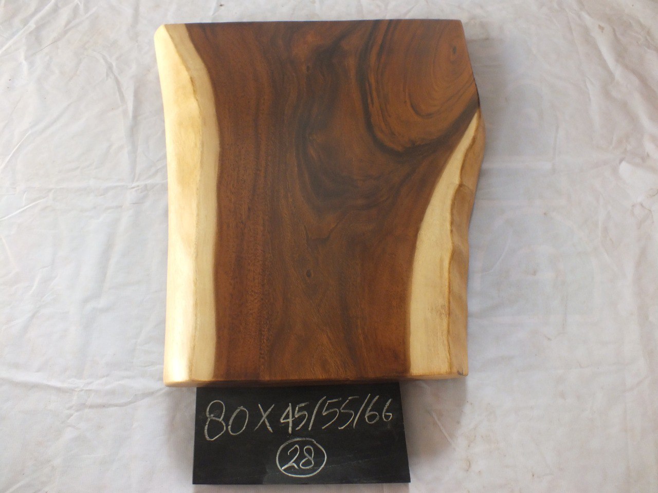 Top view of suar wood slab 0028-455566 with dramatic widening live edge shape and rich brown natural wood grain, solid single-piece countertop.
