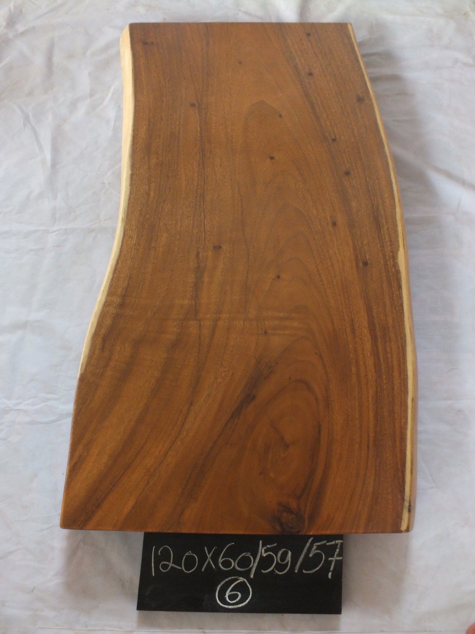 Top view of suar wood slab 0006-605957 with gently narrowing live edge shape and warm brown natural wood grain, solid single-piece countertop.
