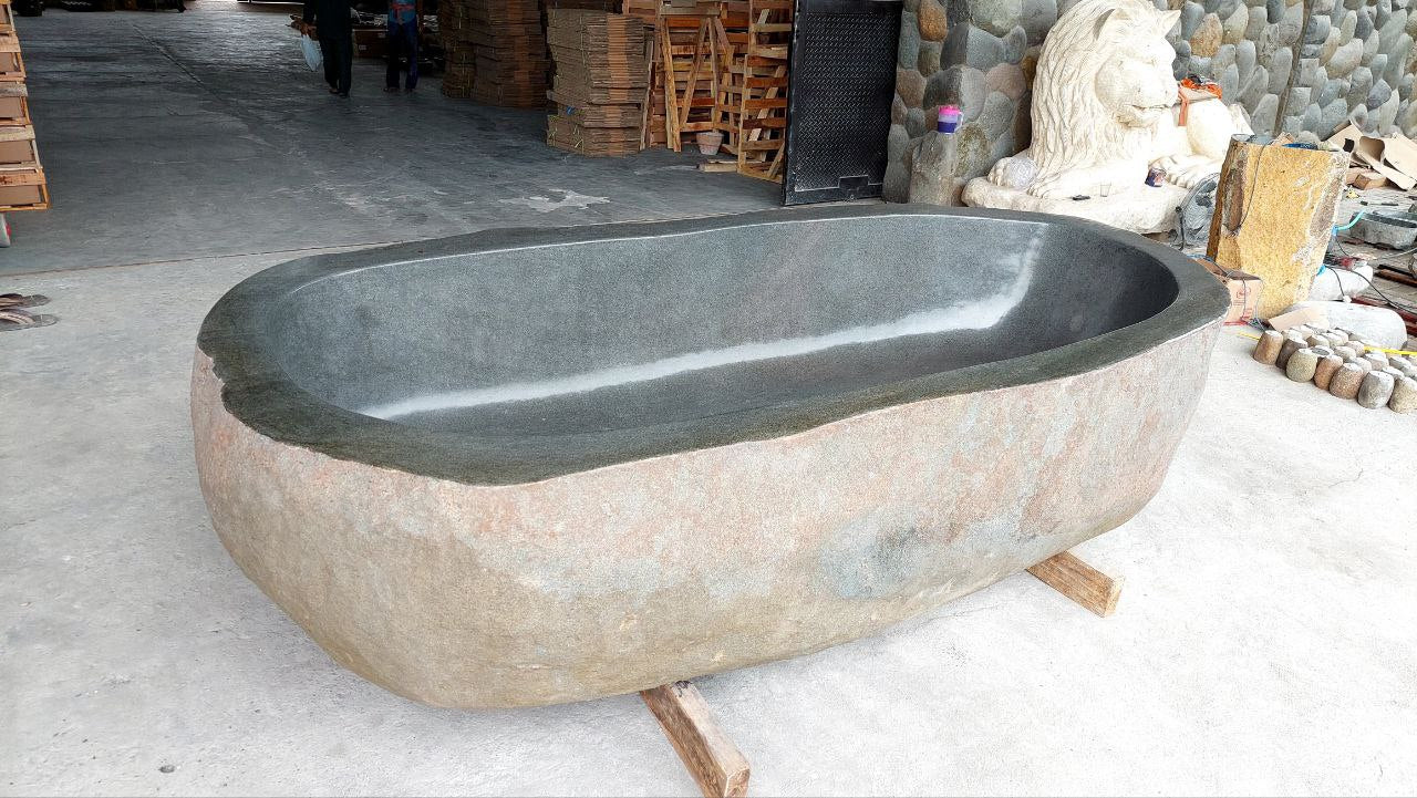 Top view of oversized river stone bathtub with polished interior
