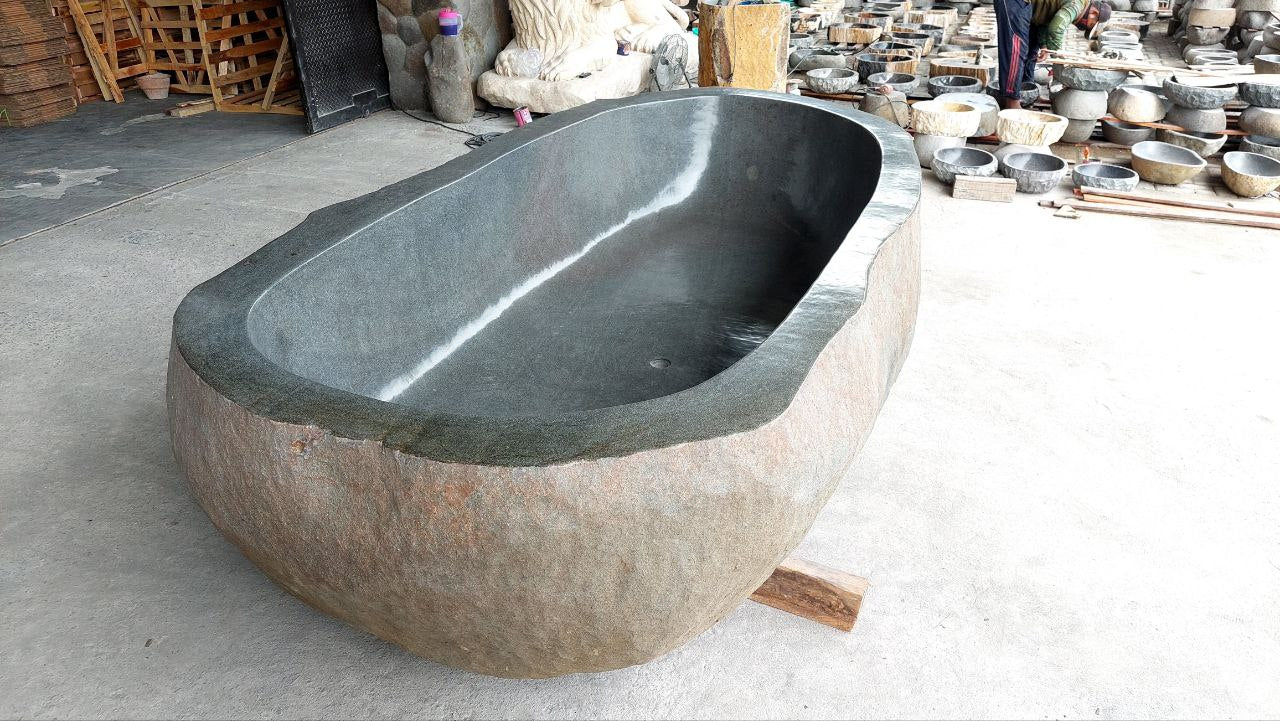 Side angle of natural river stone bathtub showing rugged exterior
