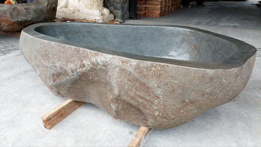 Top view of large river stone bathtub with polished interior

