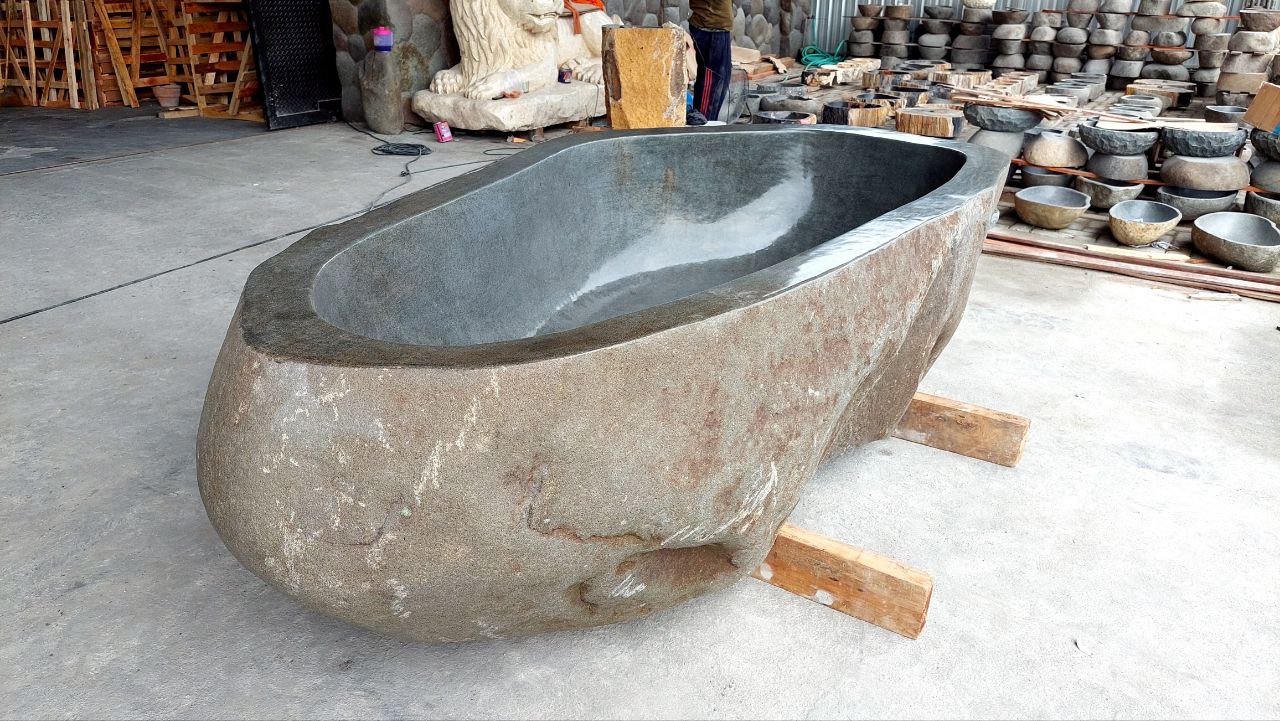 Freestanding oval bathtub carved from natural river stone
