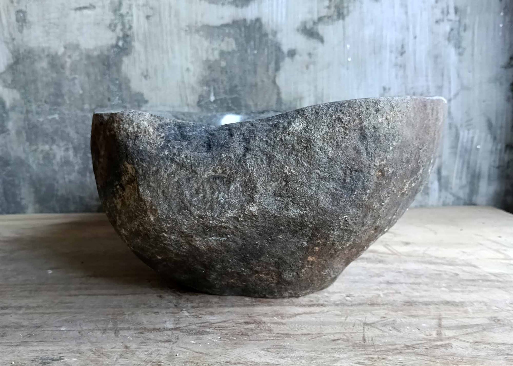 Right side view of rustic brown oval river stone sink with polished interior and rough exterior texture

