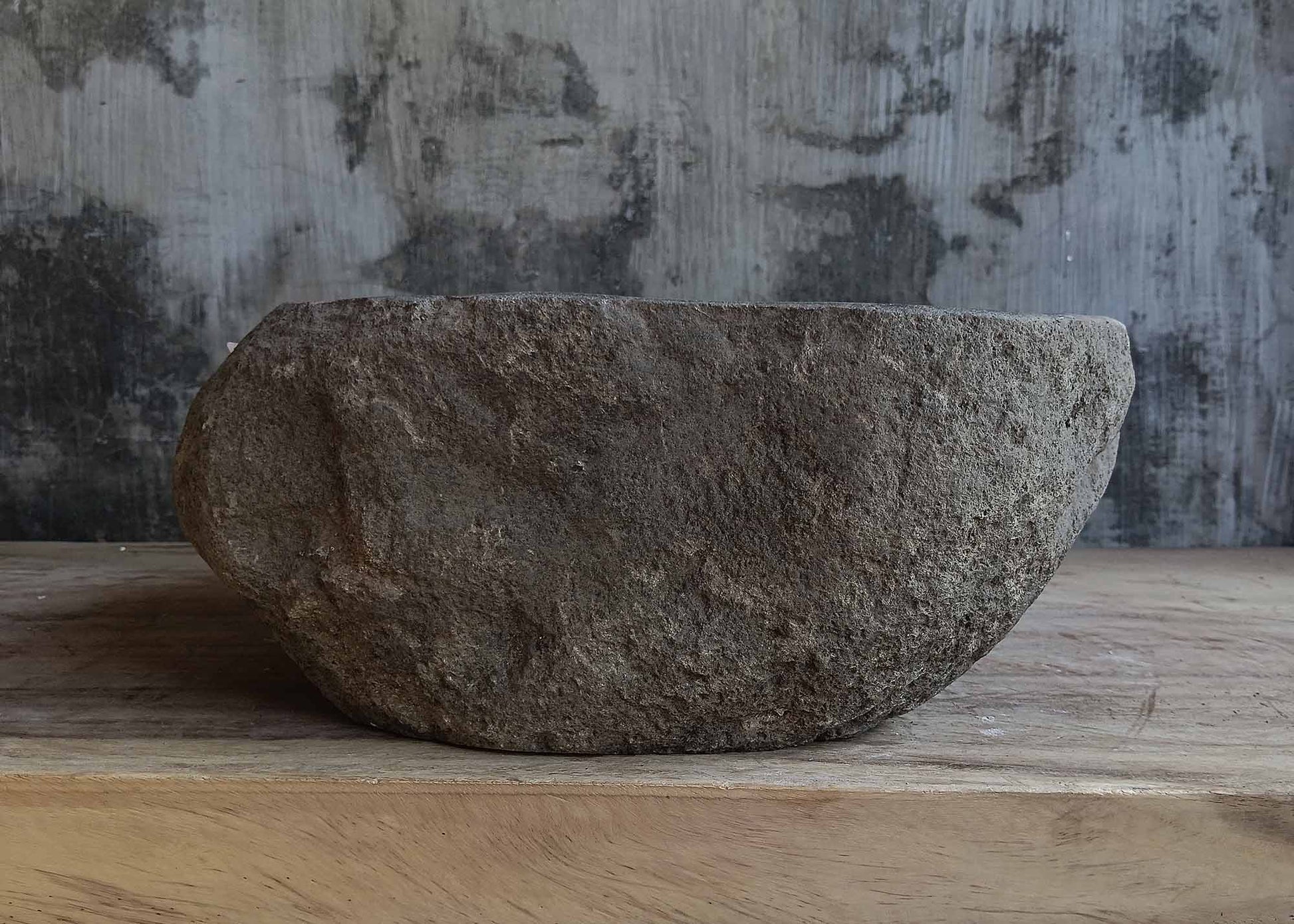 Left side view of round dark gray river stone sink 6647-3737 with rough exterior
