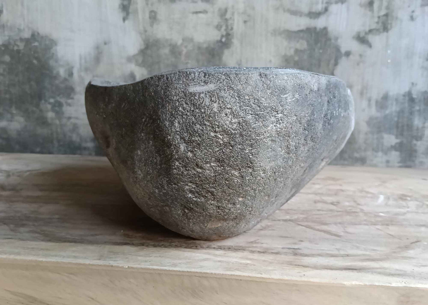 Left side view of handcrafted 17×13 inch stone sink with curved lines and raw finish
